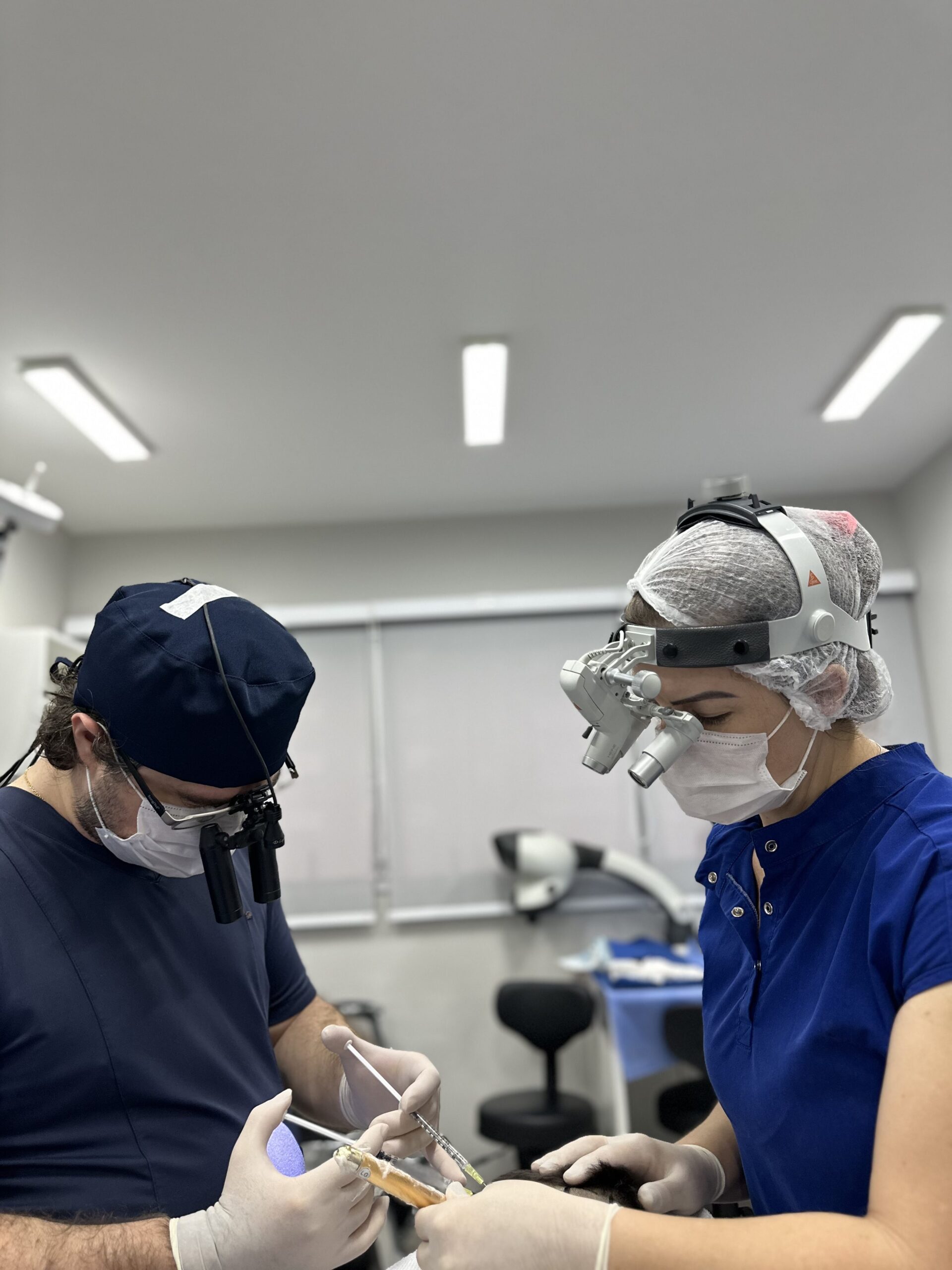 Two members of the clinical team working during a hair transplant procedure